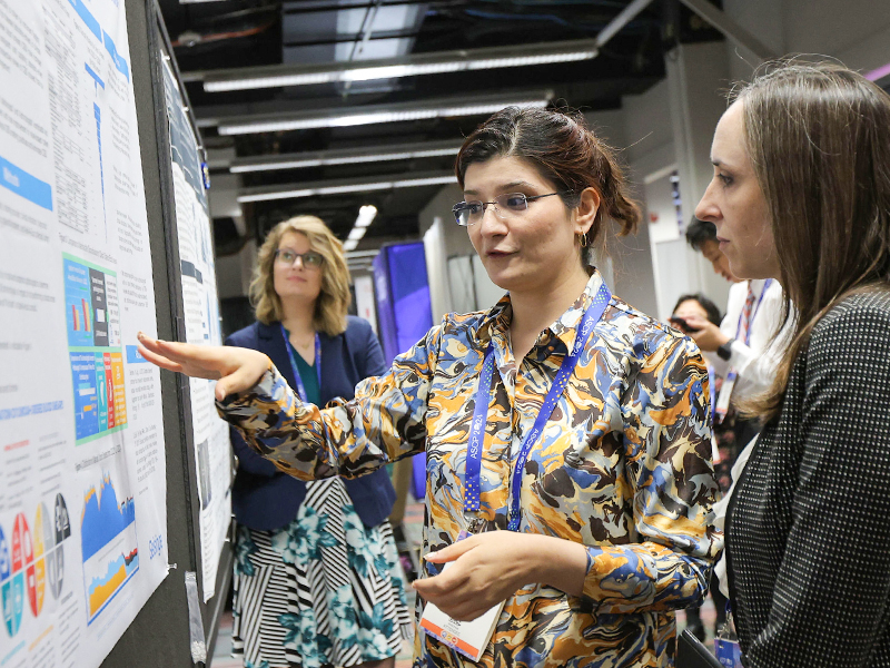2024 annual meeting attendees talking and pointing at poster