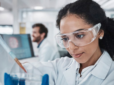 Woman wearing goggles holding pipette